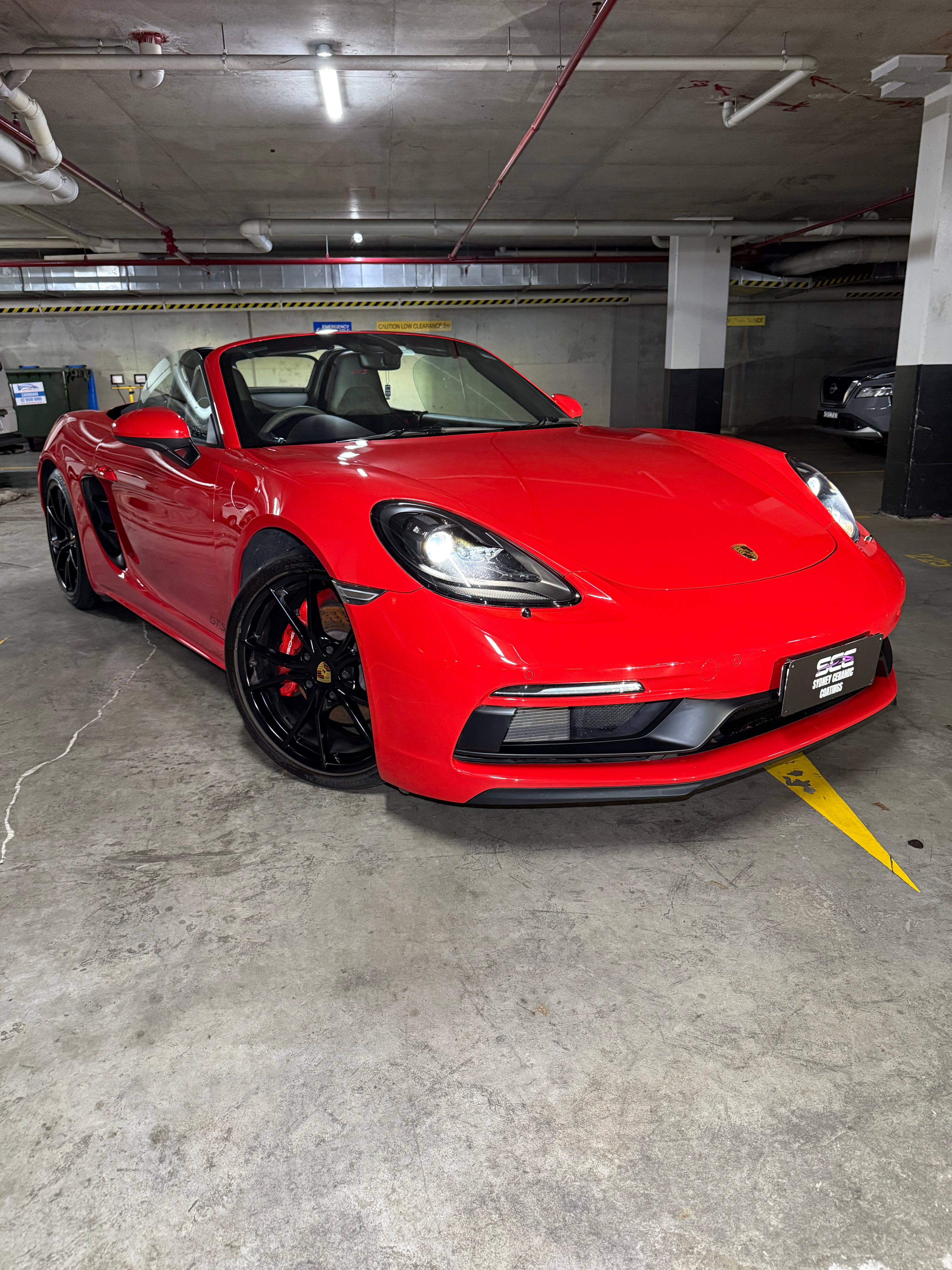 Red sports car parked inside a building with concrete floor
