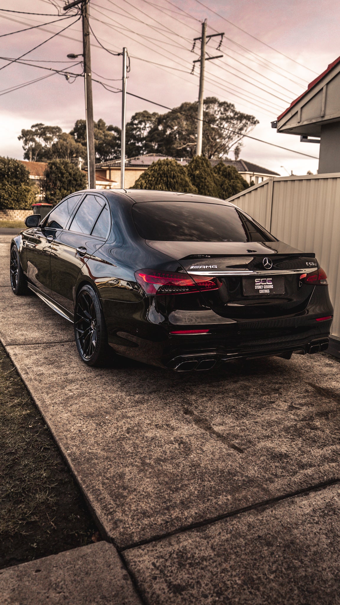 Black Mercedes-Benz car parked on a driveway with a residential background