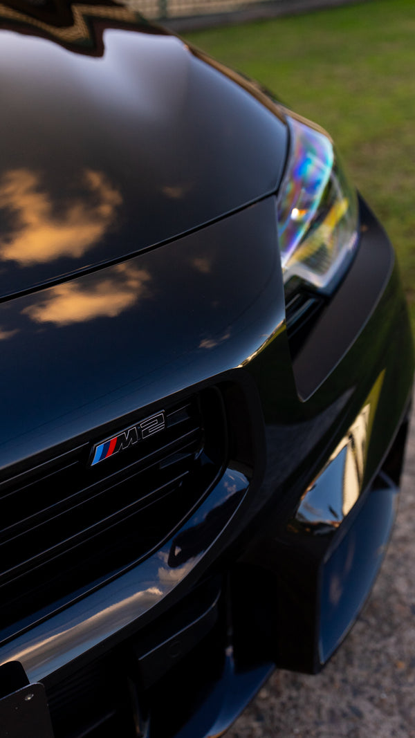 Close-up of a black car's front grille with visible branding.